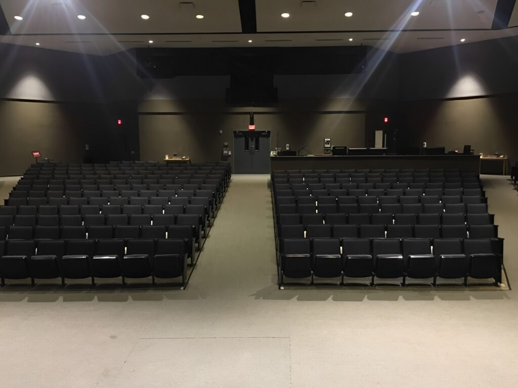 Spacious and immaculate auditorium, exemplifying professional commercial cleaning services, with spotless seating, polished floors, and a well-maintained stage area, showcasing a high standard of Optimum cleaning services cleanliness suitable for corporate and public events.